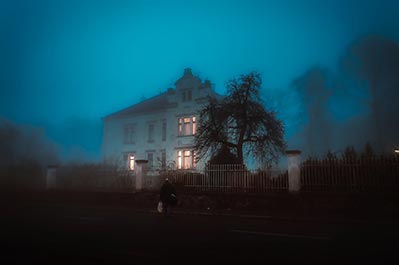 Dimly lit photograph of a home in a deep fog