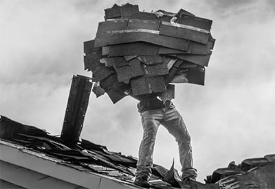Person removing shingles from a roof