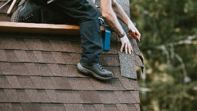 Person installing shingles on roof