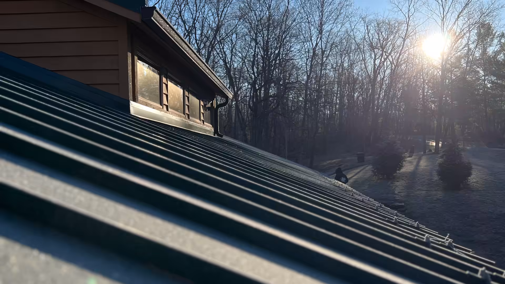 Close-up of a new metal roof installed on a home by Brandstetter's KangaRoof in Greater Cincinnati with trees and a sunny sky in the background